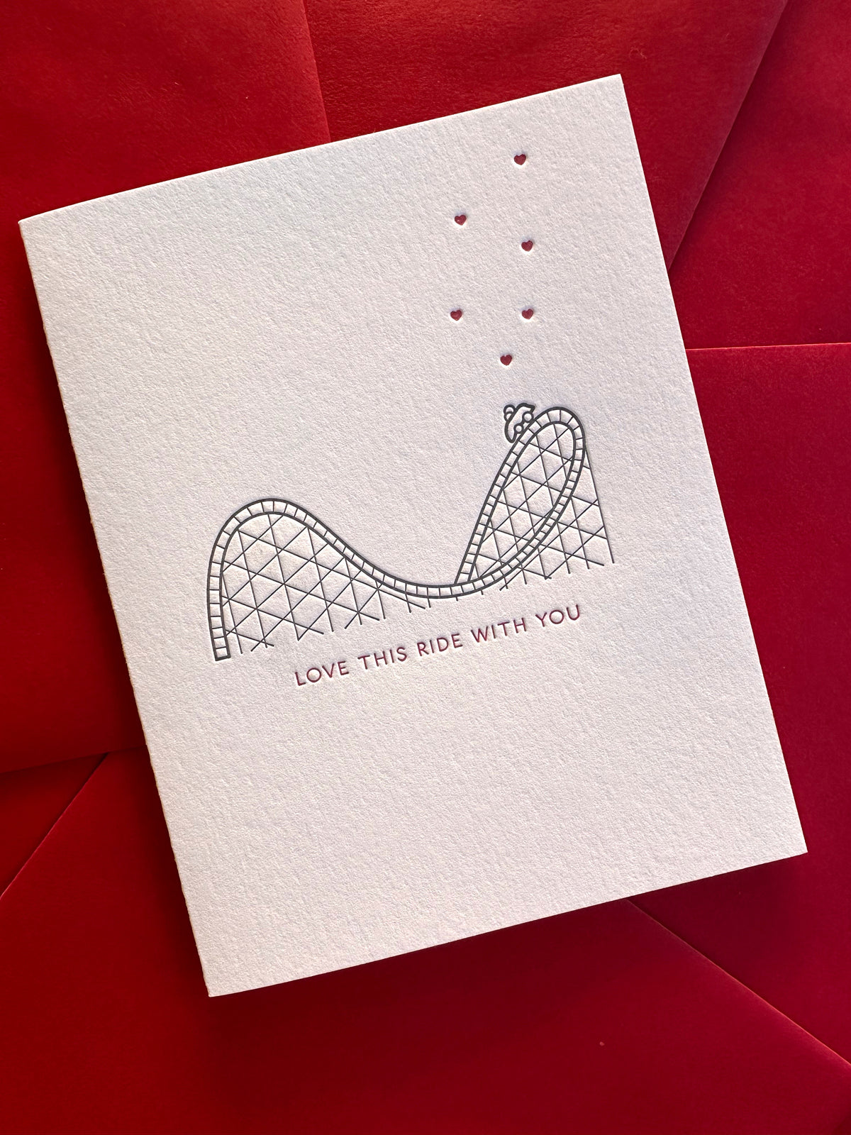 Close-up of letterpress printed rollercoaster and hearts on romantic love card