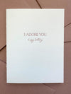 Letterpress birthday card with “I Adore You” text in dusty rose ink on bright white cotton cardstock, paired with a dusty rose envelope