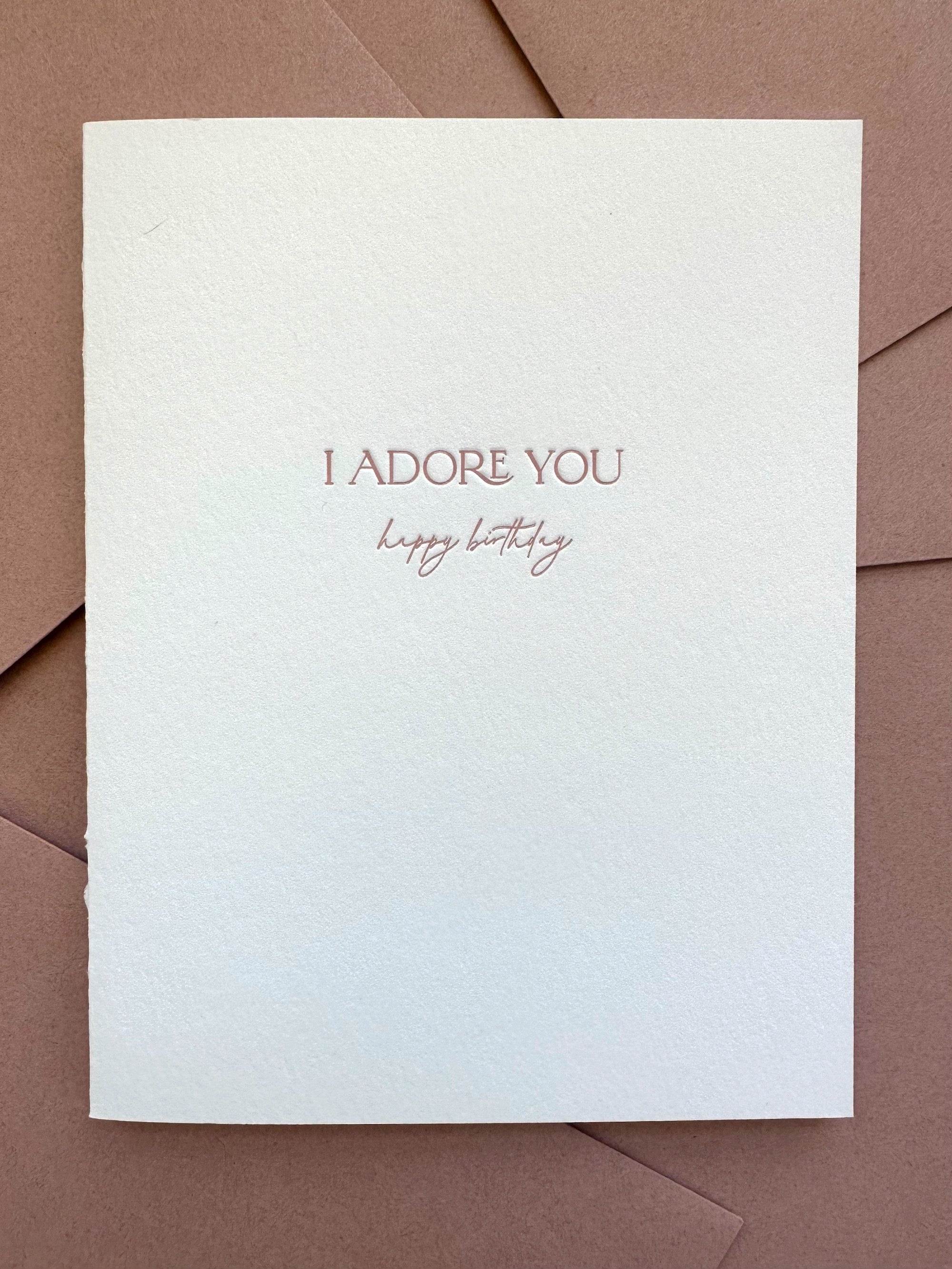 Letterpress birthday card with “I Adore You” text in dusty rose ink on bright white cotton cardstock, paired with a dusty rose envelope