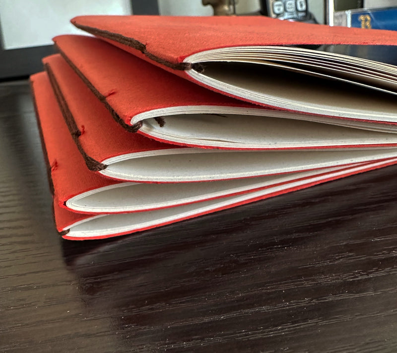 Close-up of hand-bound spine with matching thread on persimmon handmade paper Thanksgiving journal