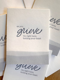 As you grieve, I'm right here, holding you heart. A folding white sympathy card. Letterpress printed luxury for those who need a hug.