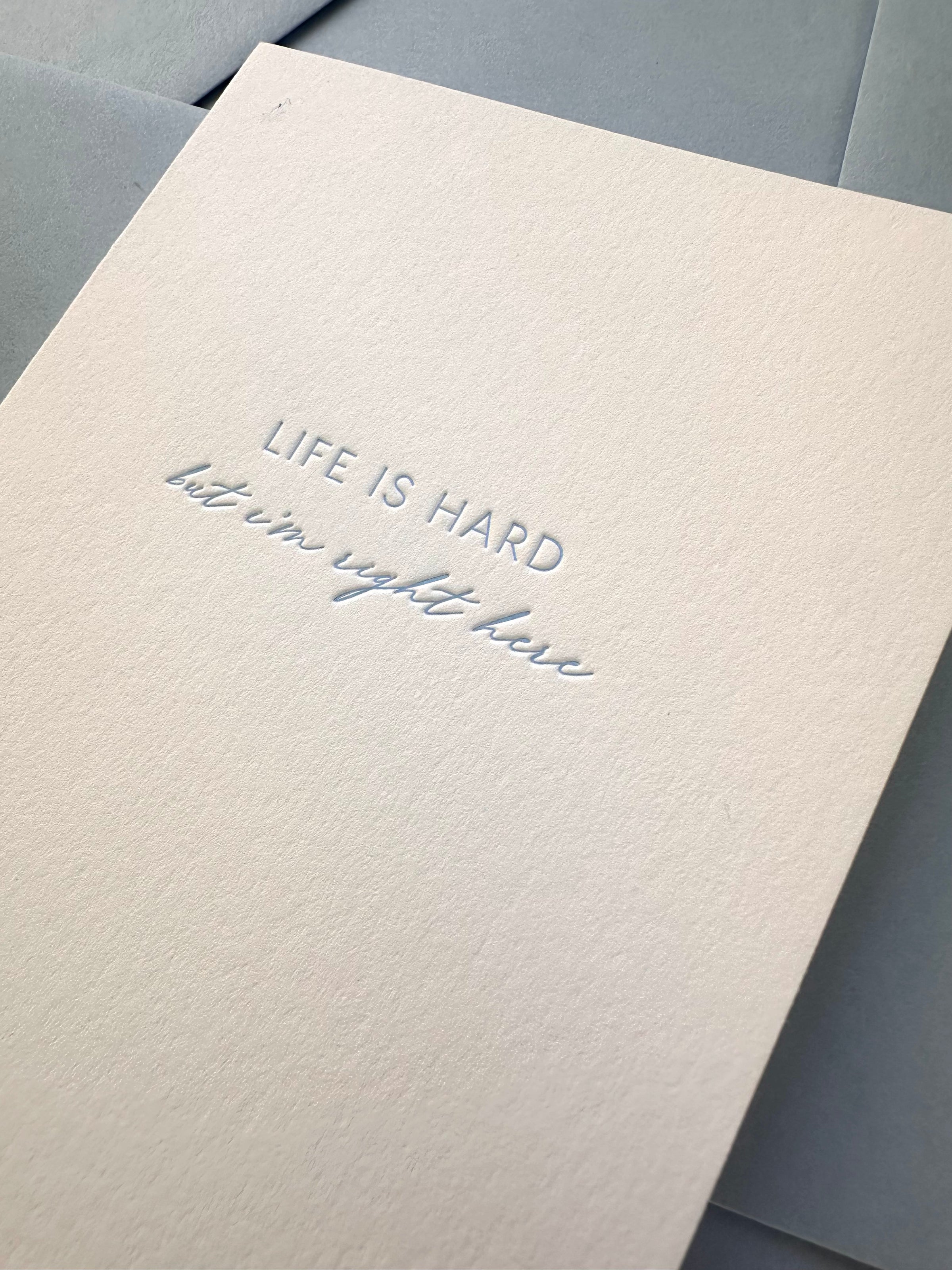 Letterpress close up of a card for someone struggling. It says "Life is hard, but I"m right here."